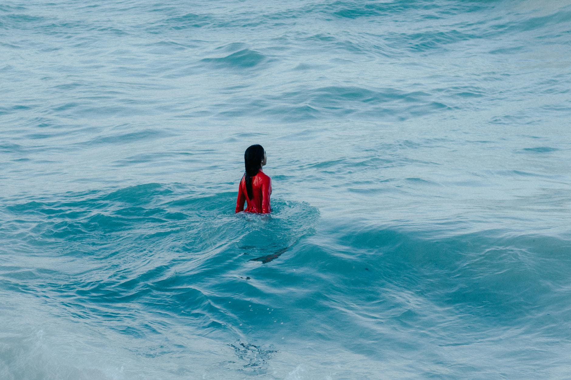 A woman in a red outfit swimming in the ocean at Canoa Quebrada beach, Brazil.