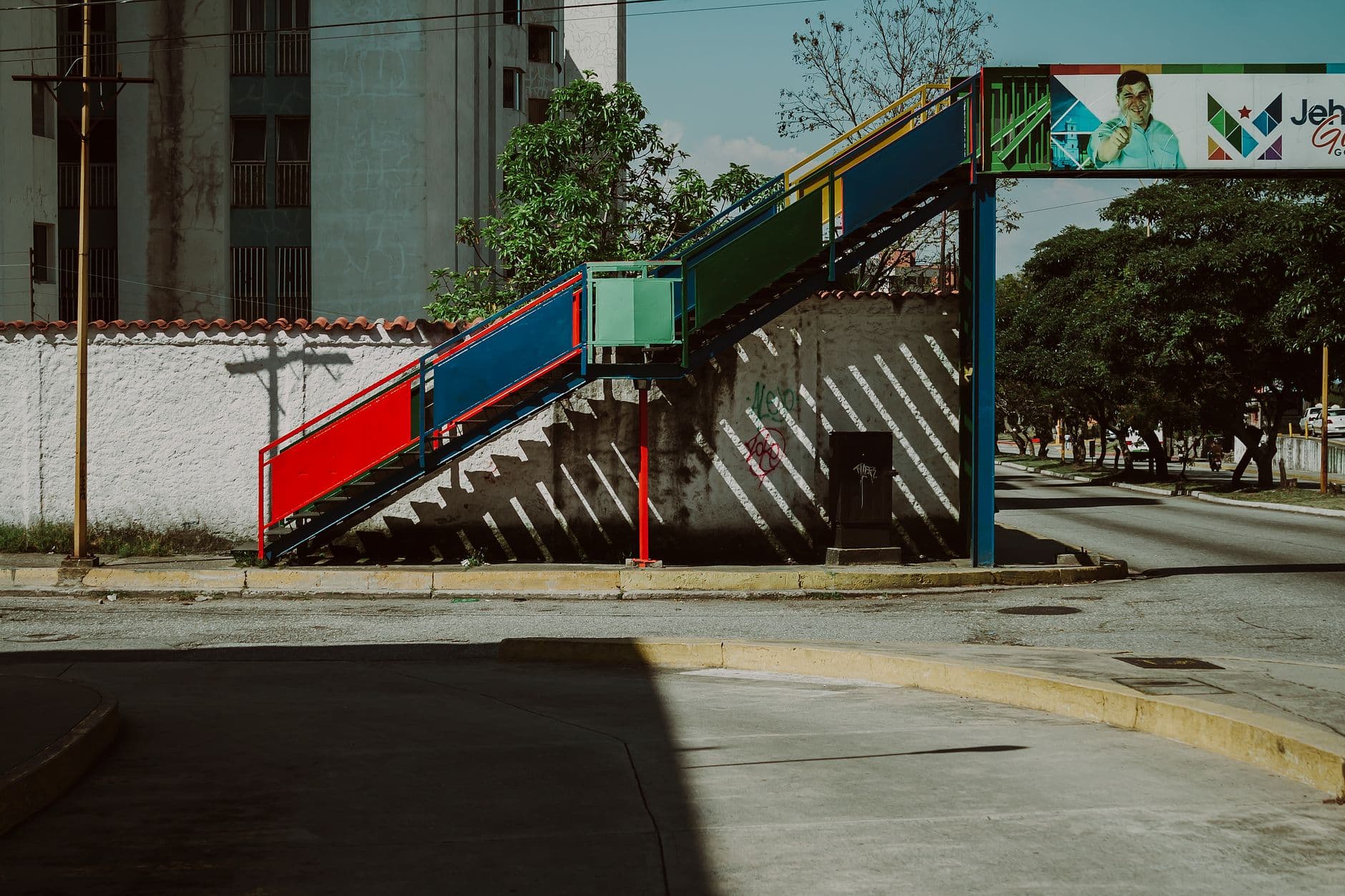 A vibrant pedestrian bridge over quiet urban streets in Mérida, Venezuela.