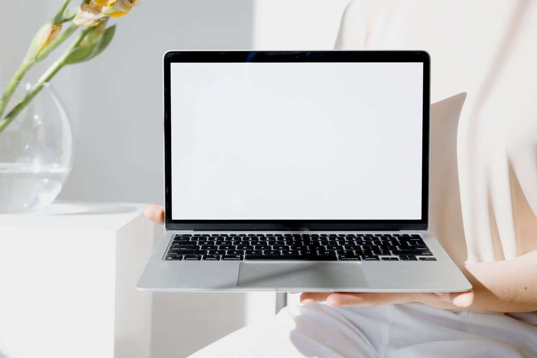A blank-screen laptop held by a person in a modern, bright setting. Perfect for mockup use.