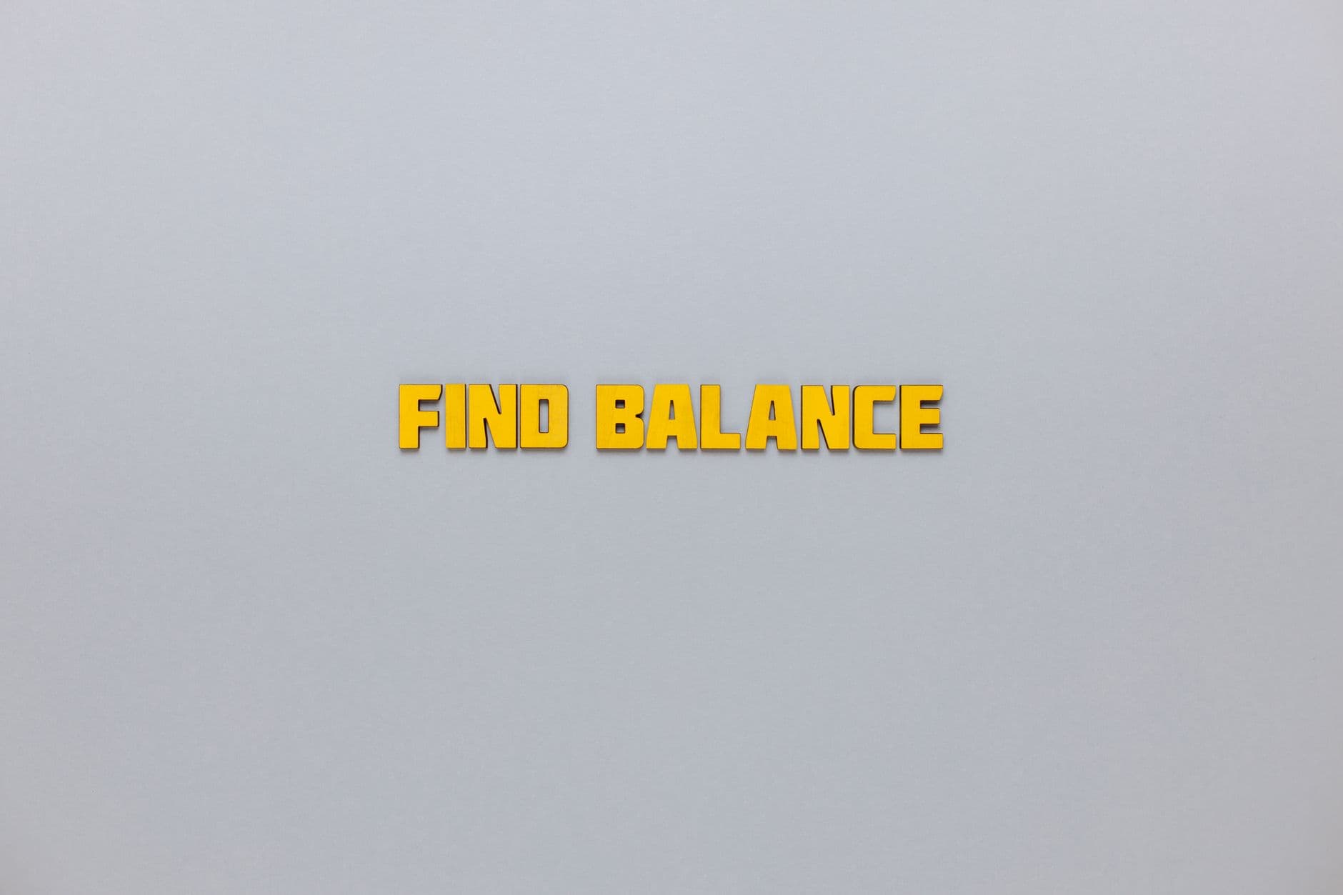 Yellow text 'Find Balance' displayed on a minimalist grey backdrop for motivation.