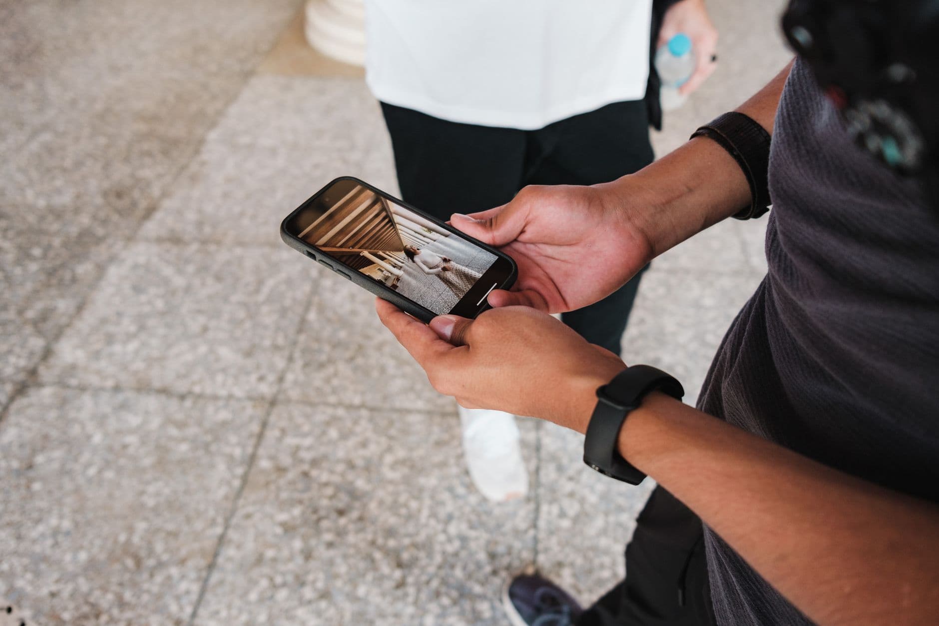 A person holding a smartphone displaying a photo, highlighting casual urban smartphone use.
