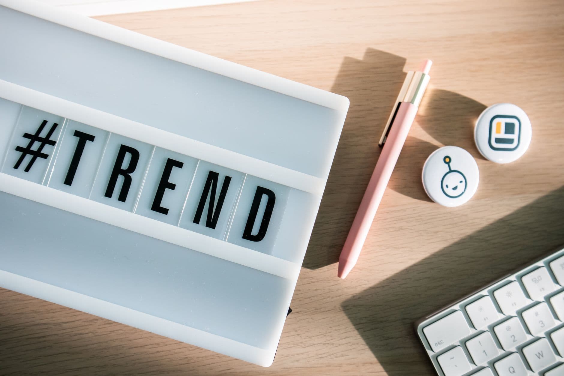 Stylish desk setup with a trendy lightbox, keyboard, and pink pen for modern office vibes.