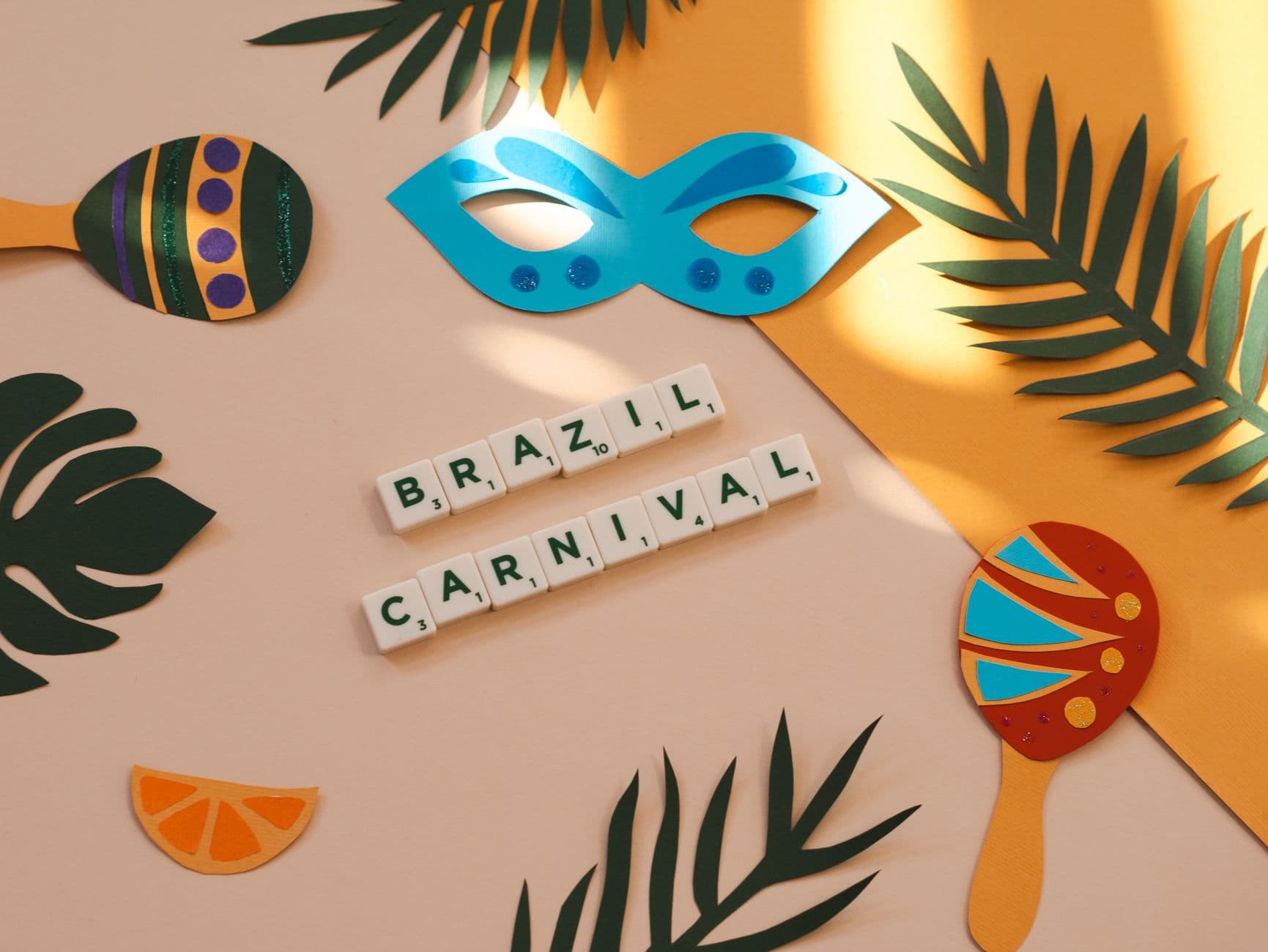 Colorful flat lay of Brazil Carnival with mask, maracas, and foliage.