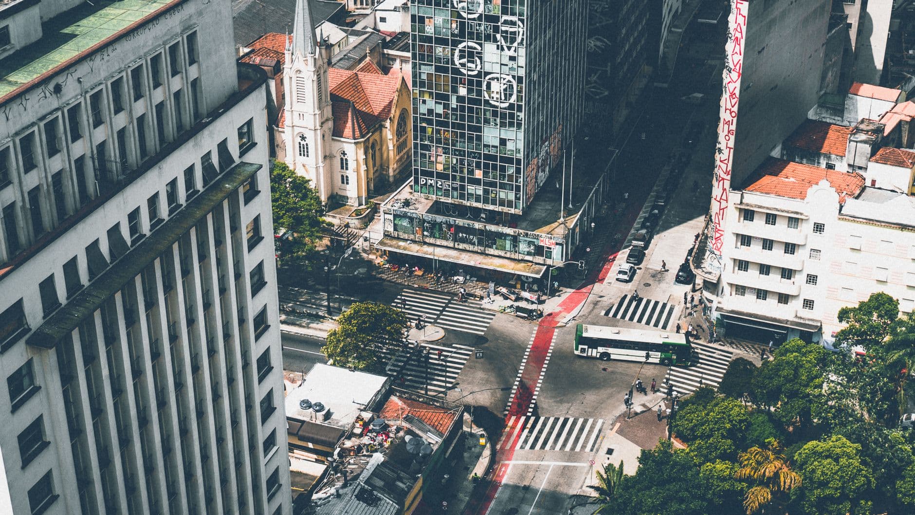 A bustling city intersection with modern skyscrapers and a church visible.